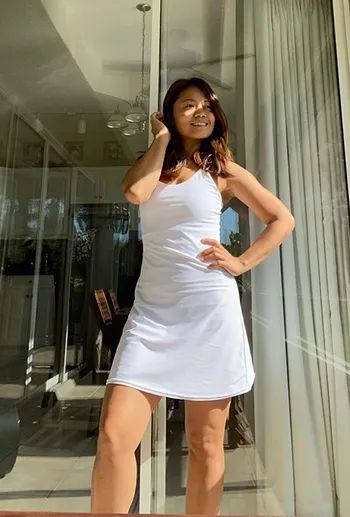 Reviewer wearing a white mid-length athletic dress with strappy details