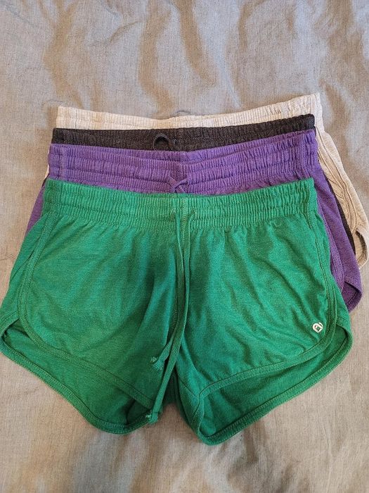 Three neatly folded pairs of athletic shorts displayed on a textured fabric background.
