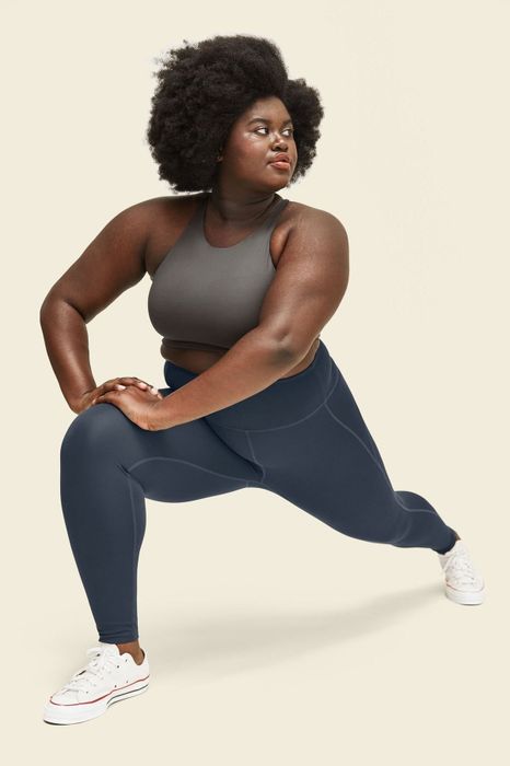 Model wears dark blue high-rise leggings paired with a gray sports bra