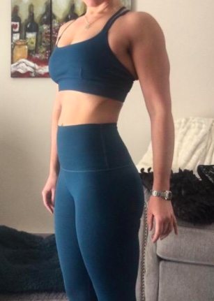 The reviewer displays the front view of a blue criss-cross sports bra, highlighting its stylish design.