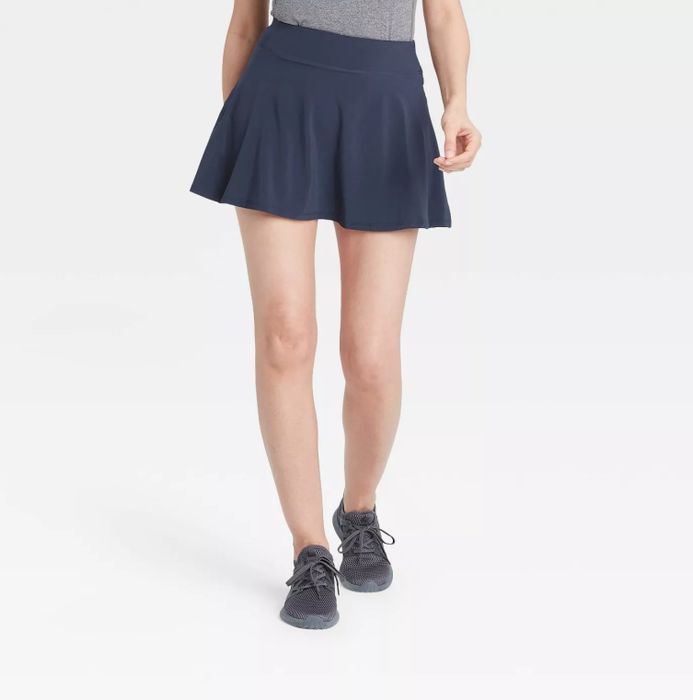 A model wearing the navy blue skort paired with gray sneakers and a light gray top