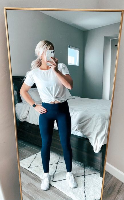 Reviewer taking a mirror selfie in a knotted white t-shirt paired with blue leggings