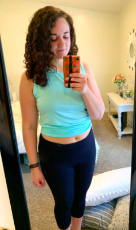 Reviewer wears the same style tank in a light blue shade with black workout capris