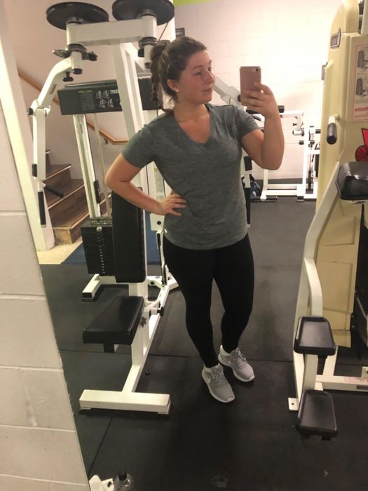 Reviewer posing for a mirror selfie in a gym, dressed in workout attire