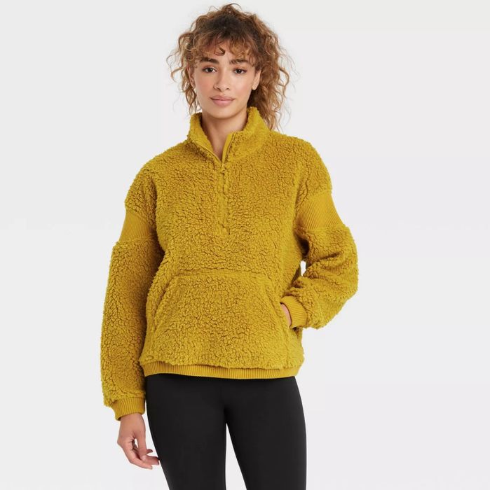 The model is styled in a gold Sherpa pullover paired with black leggings.