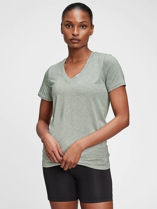 Model wearing a light green V-neck tee paired with black bike shorts