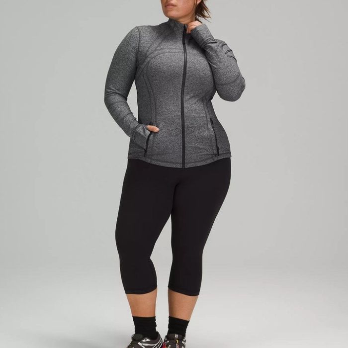 A model displaying the same zippered athletic jacket in a classic heather grey shade.