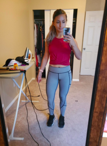 Reviewer models the same workout crop top in a red color paired with gray leggings