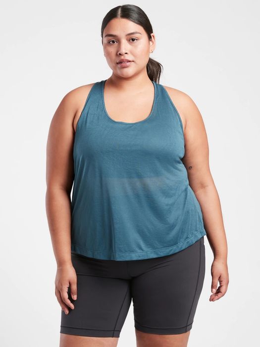 The model is wearing a breezy, semi-transparent blue workout tank paired with matching leggings.