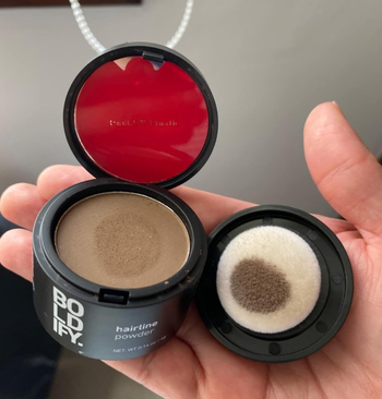 A reviewer holding the compact powder with its sponge applicator