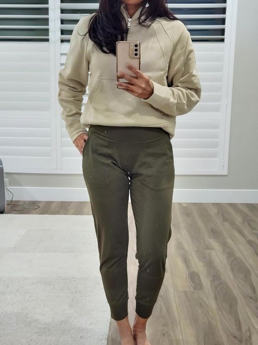 Individual in a relaxed sweatshirt and joggers capturing a mirror selfie, highlighting their outfit