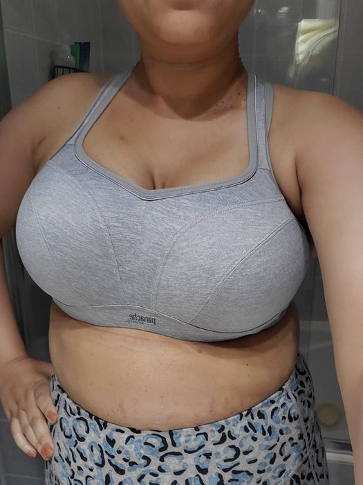 The reviewer is wearing the same style of sports bra, but in a sleek gray shade.