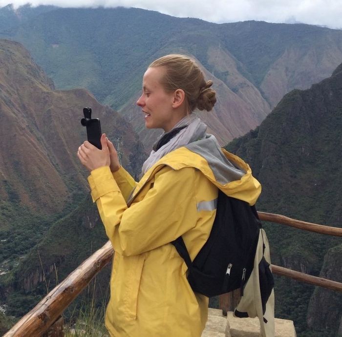 The reviewer is seen wearing a bright yellow wind- and waterproof rain jacket while hiking in Peru.