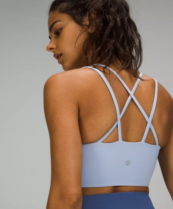 A model showcasing a longline sports bra in blue denim with cross-back straps.