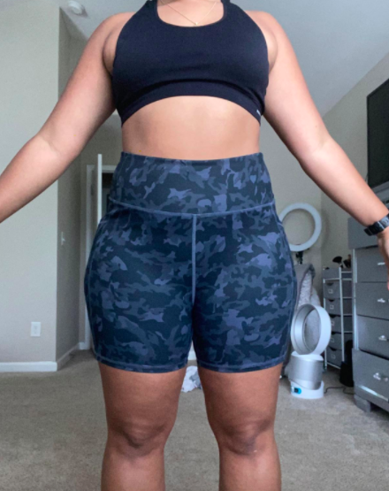 The reviewer is wearing the same style of bike shorts, this time in a swirling dark blue design, matched with a black sports bra.