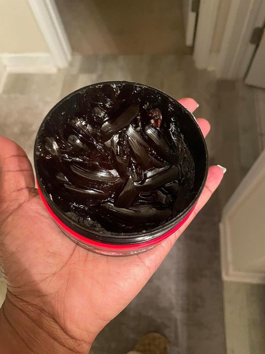 reviewer holding a jar of the ultra-hold styling wax