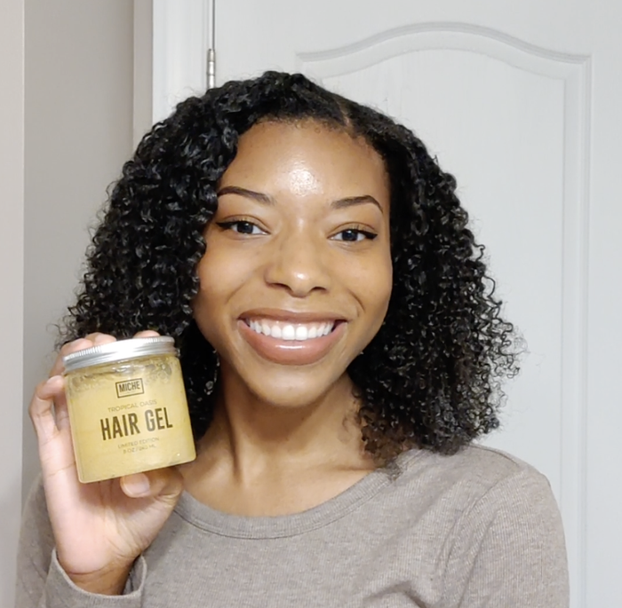 Me smiling while holding a jar of the hair gel