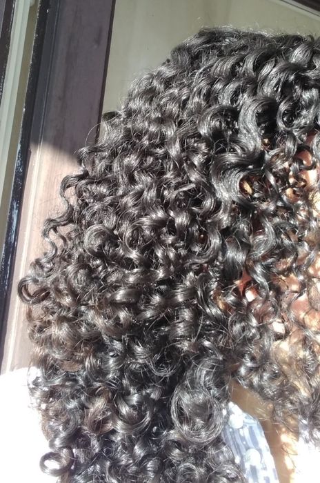 Reviewer showcasing tight curls with added shine from the product