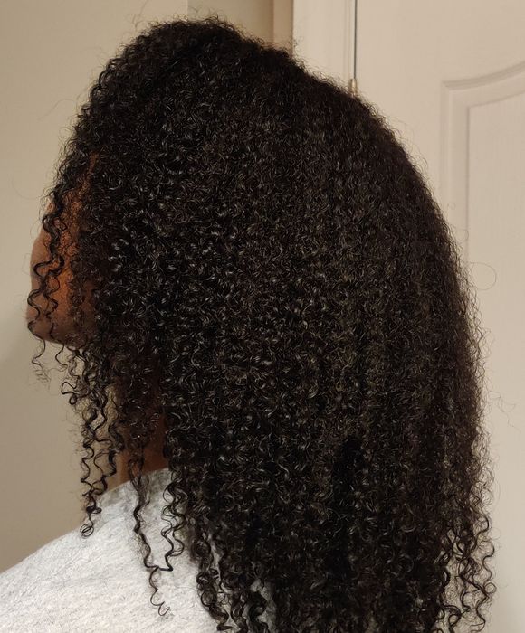 A side profile of a person with shoulder-length curly hair.