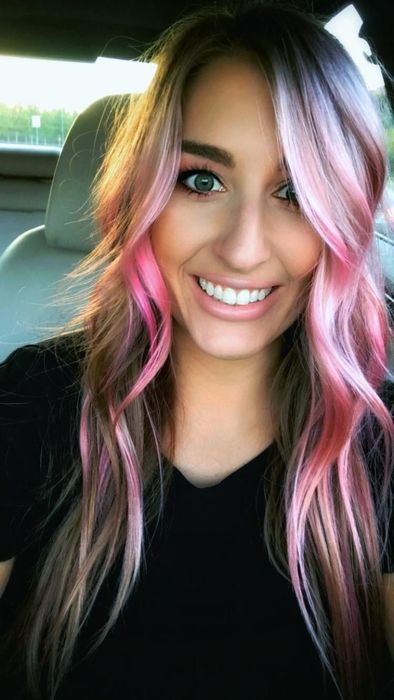 A reviewer showcasing vibrant pink hair achieved by using the product