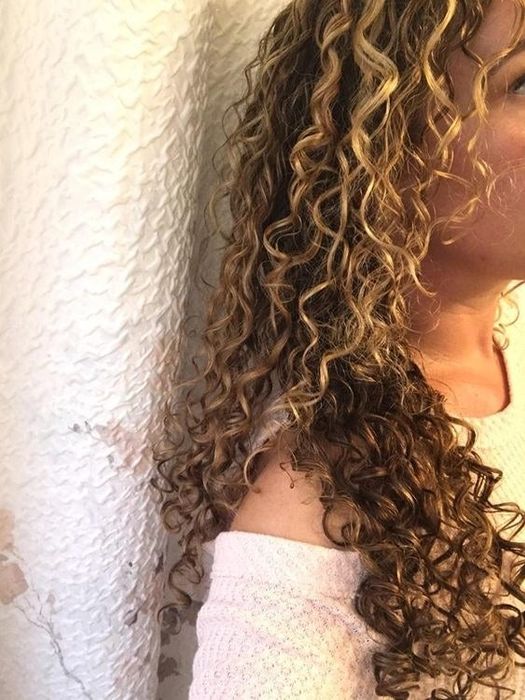 A reviewer with long wavy curls displaying the results after applying the pudding