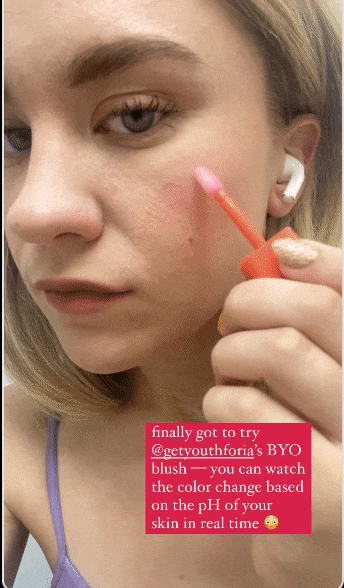 editor applying a clear blush to their cheeks as it transforms into a soft pink hue
