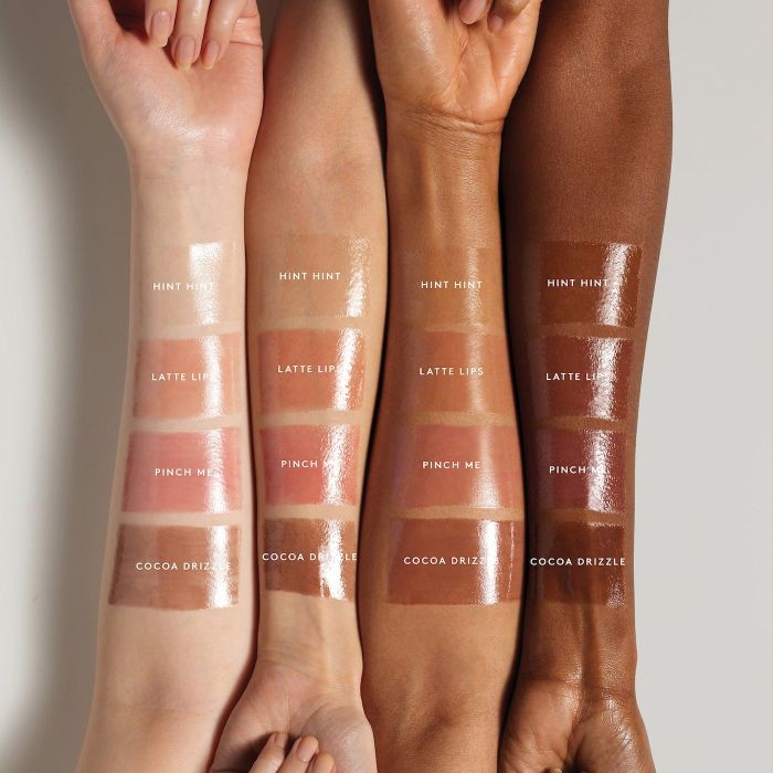 Four arms in different skin tones displaying six swatches of lip balm.