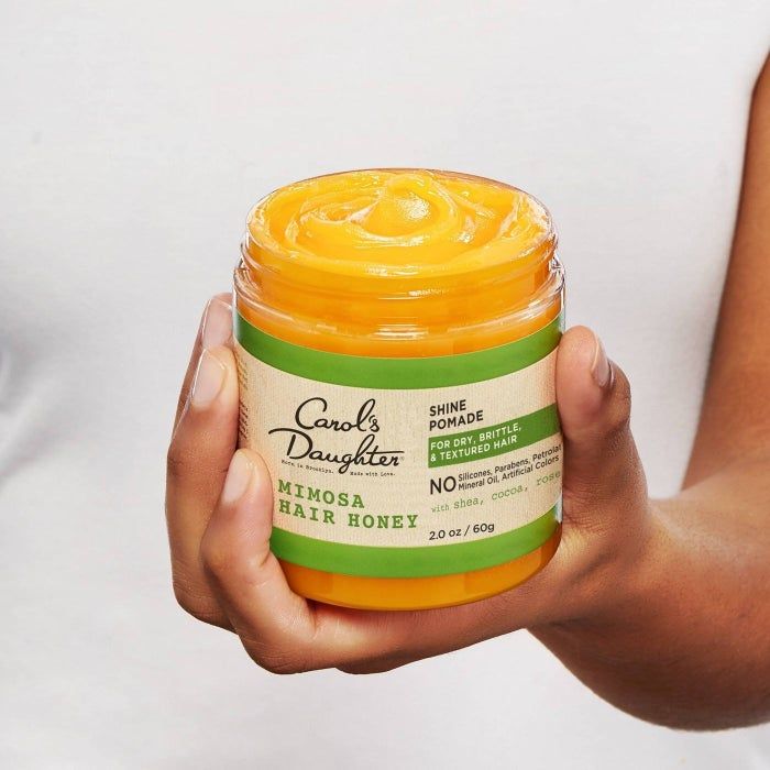 a hand grasping the jar of thick yellow whipped treatment