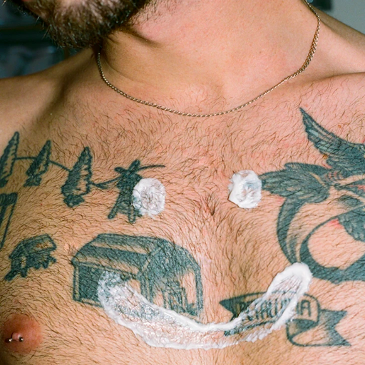 A model with a smiley face made of shaving cream on their hairy chest