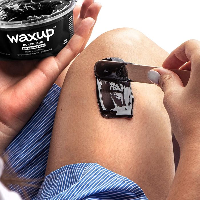 A model holds the wax pot while applying it to their knee.