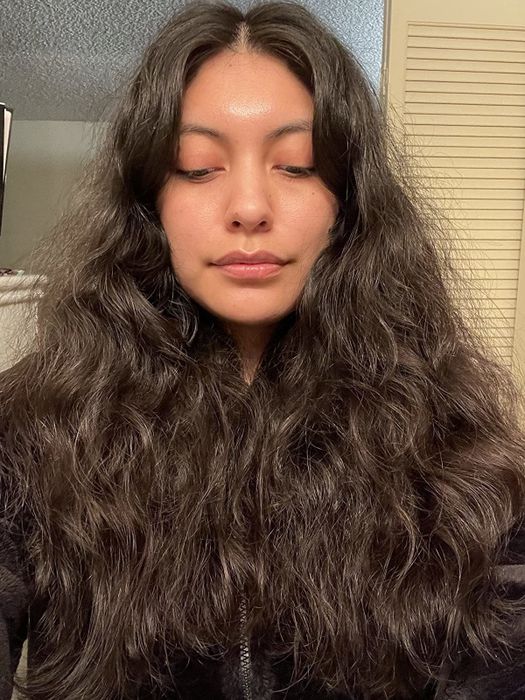 A reviewer showing their curly hair before using the brush.