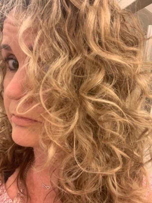 A reviewer showcasing her soft, loose waves after applying the lotion