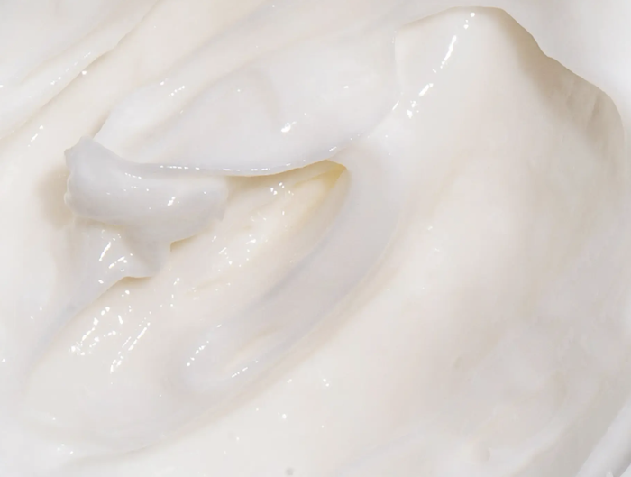 A close-up showing the creamy texture of the thick white hair mask.