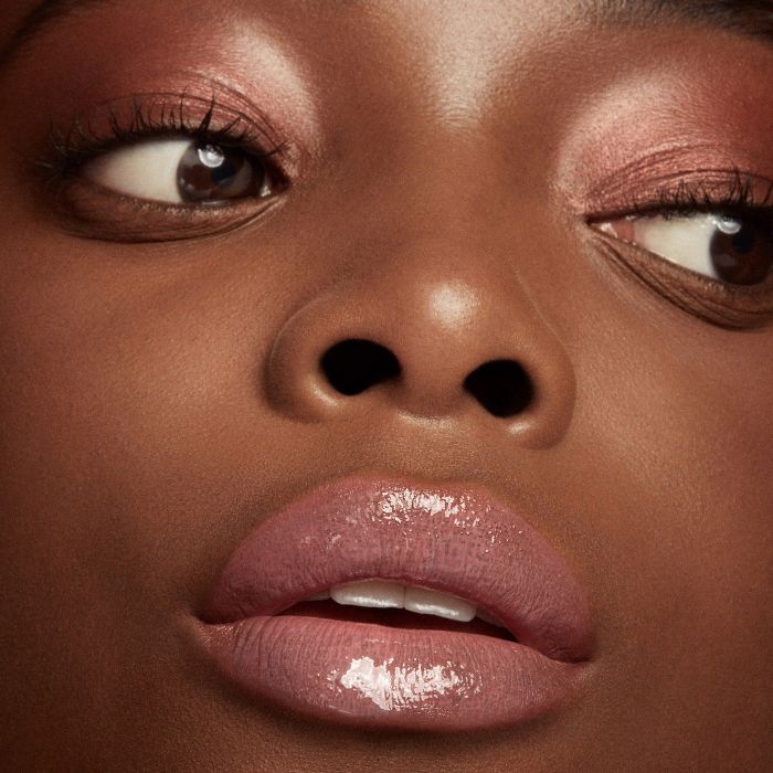 Close-up of a model's lower face, focusing on their glossy lips.