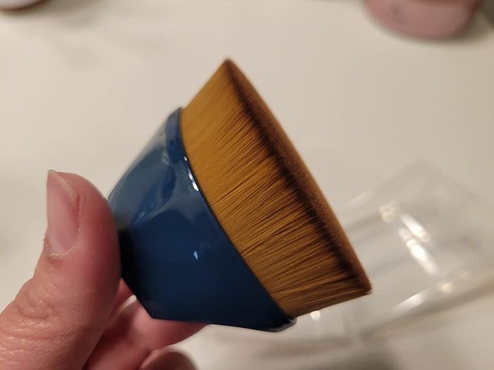 The reviewer is seen holding the blue brush