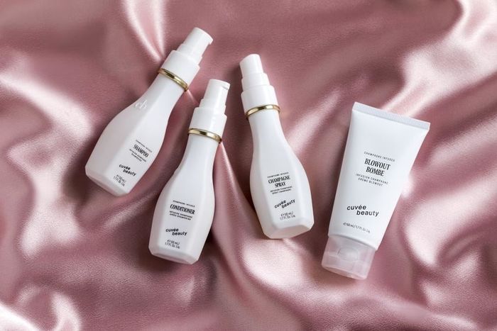 A collection of shampoo, conditioner, champagne spray, and blowout bombe
