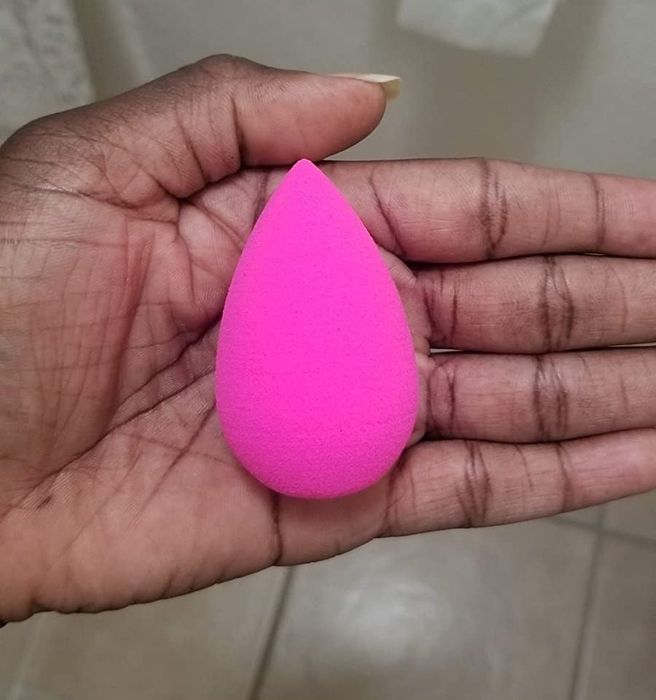 Reviewer holding the classic pink Beauty Blender sponge