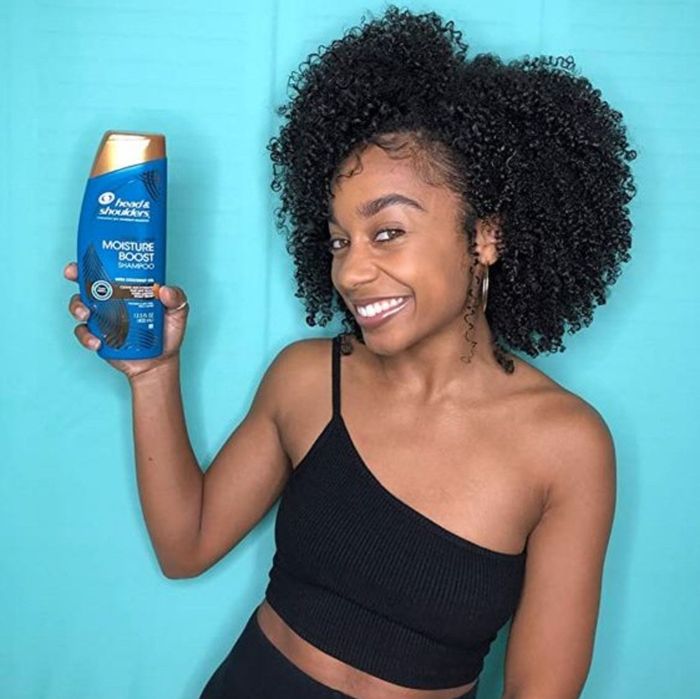 A curly-haired model holding the product
