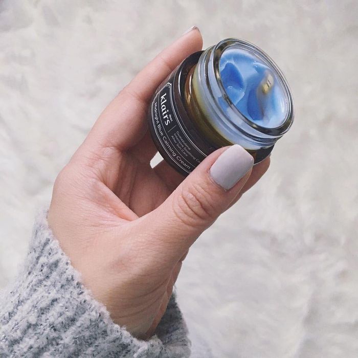 image of a reviewer holding up the small jar of cream