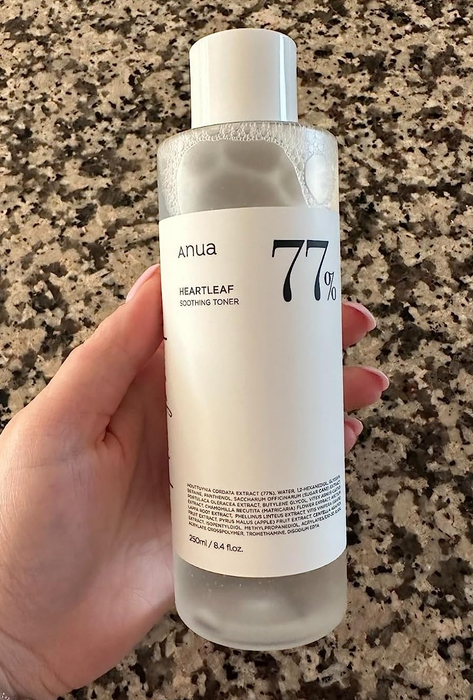 A reviewer holding a bottle of toner, showcasing the product