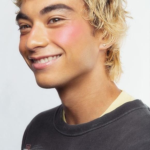 A model applying pink blush.