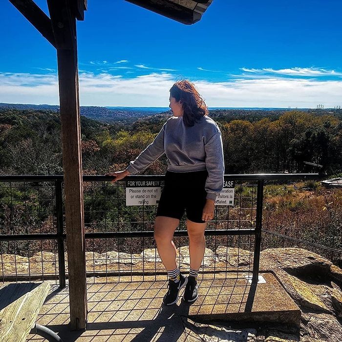 A reviewer pausing for a break at a hiking trail, dressed in black shorts.