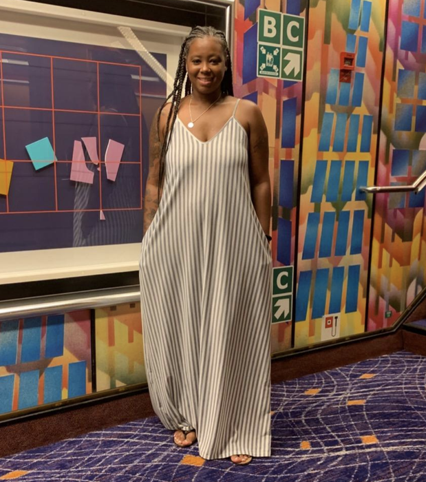A reviewer is seen wearing a gray and white striped tank dress.