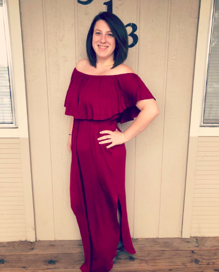 A reviewer is seen wearing a red dress with a ruffled detail at the top.