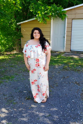 A reviewer is seen in a white dress adorned with red floral prints.