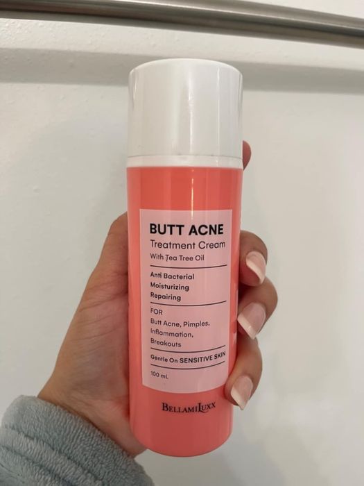 A hand holding a bottle of BellamiLuxx Butt Acne Treatment Cream
