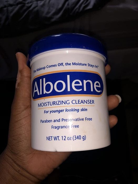 A reviewer holding the container of the cleanser