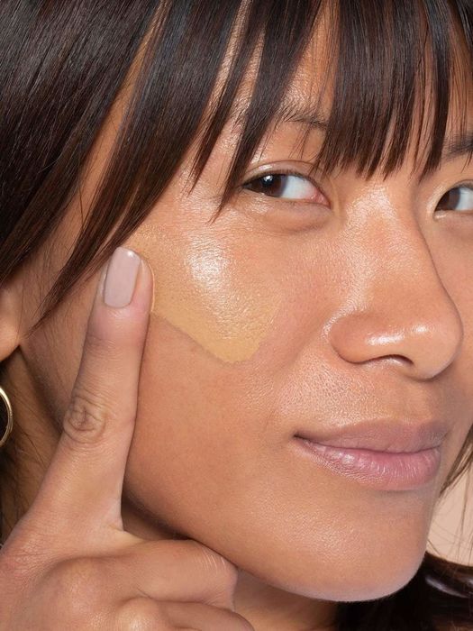 Model displaying a swatch of the product on her cheek.