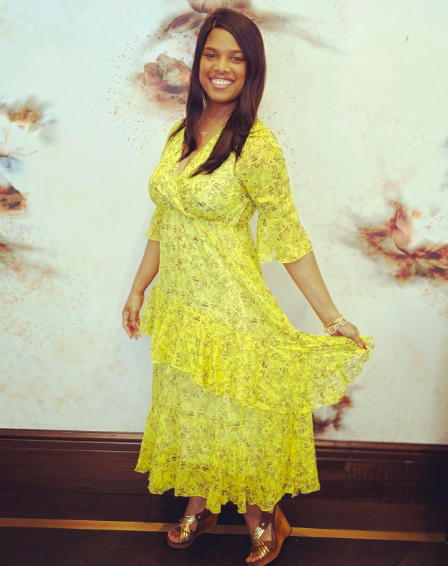 A reviewer sporting a 3/4-sleeve dress in a vibrant yellow hue.