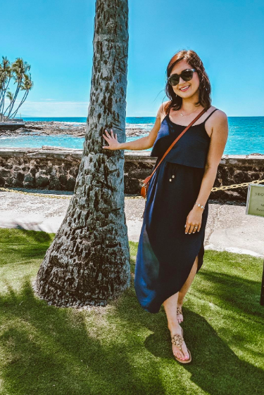 A reviewer wearing the dress in navy, featuring a rounded hemline with slits on the sides